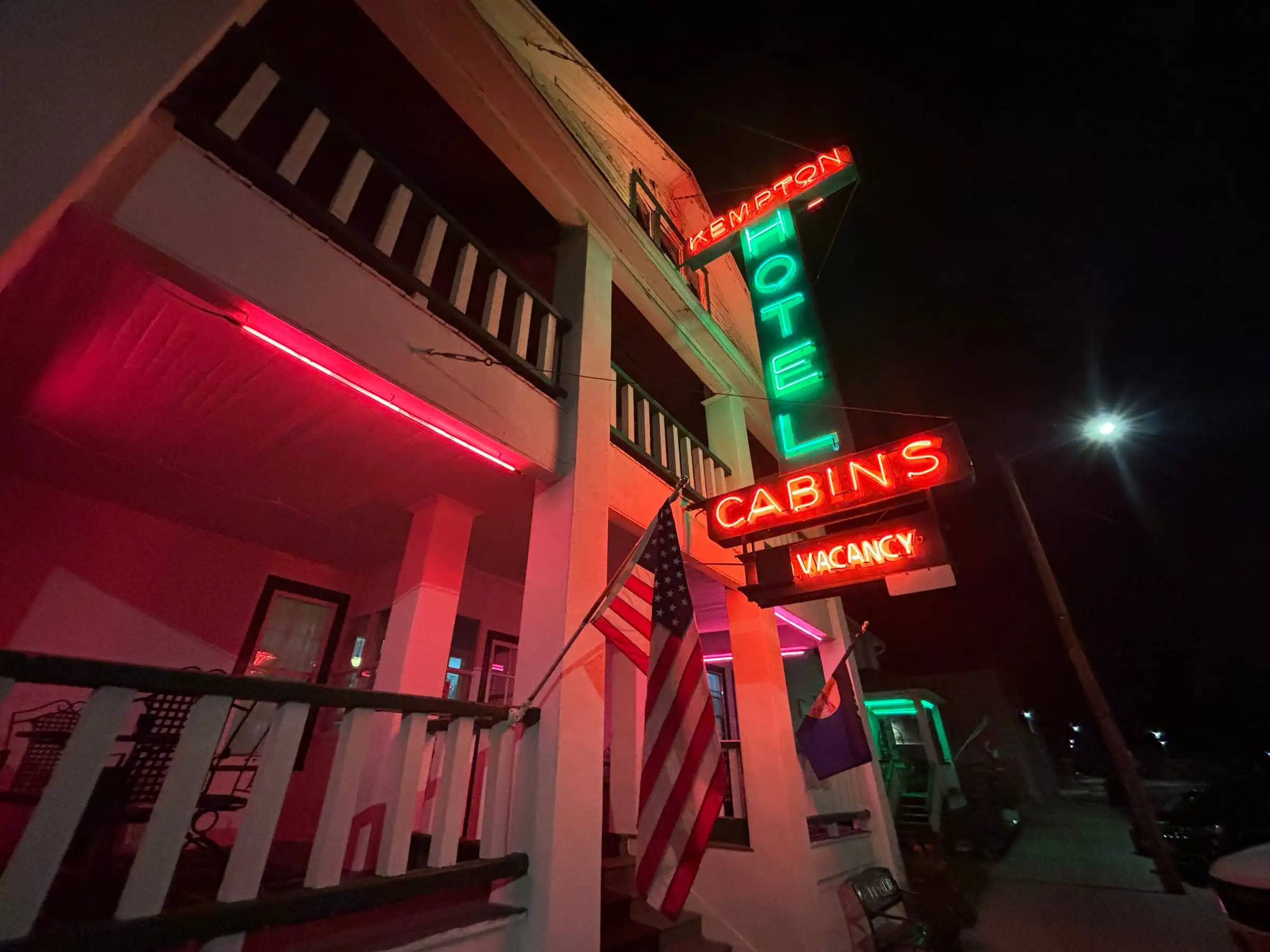The Kempton Hotel at night, its neon Hotel, Cabins and Vacancy signs glowing above the double porches