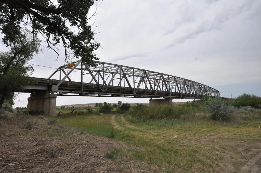 The steel truss Powder River Bridge on Old US 10, with grass and trees around it