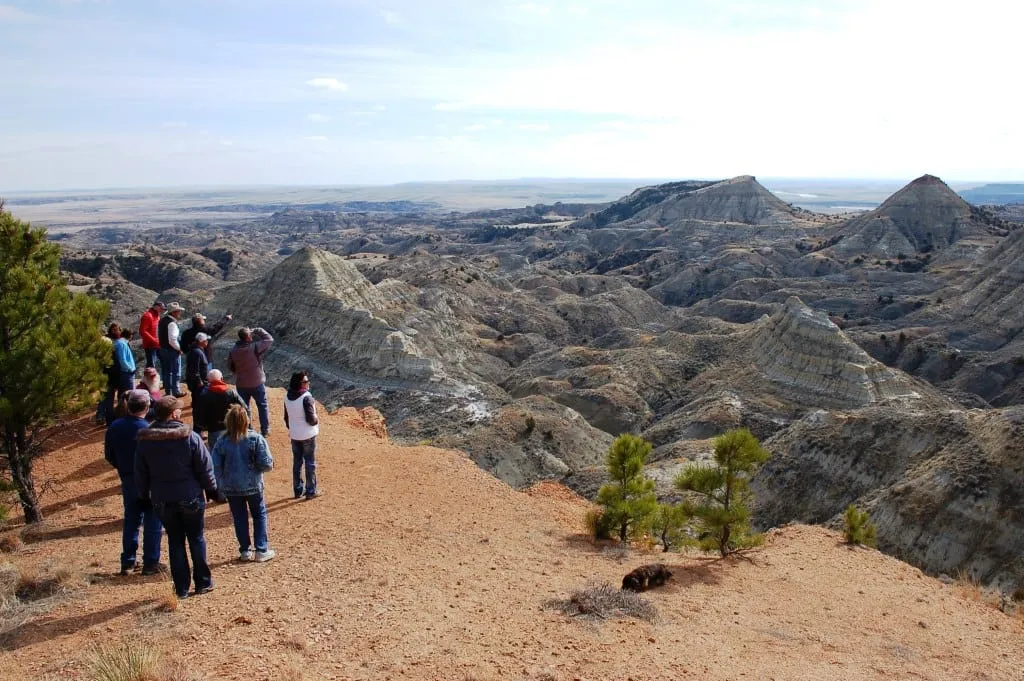 A group of visitors standing on the rim at the Terry Badlands Scenic Overlook, looking out over eroded buttes